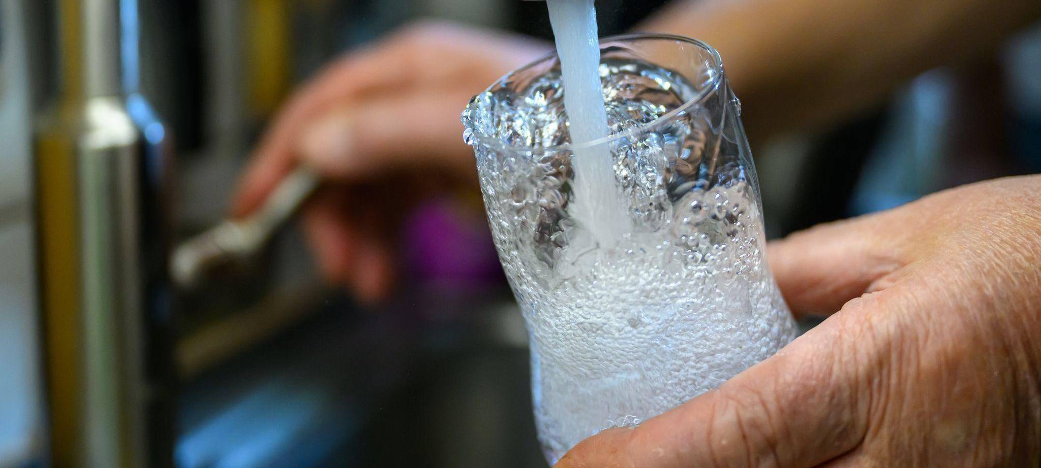 Person füllt Leitungswasser in ein Glas