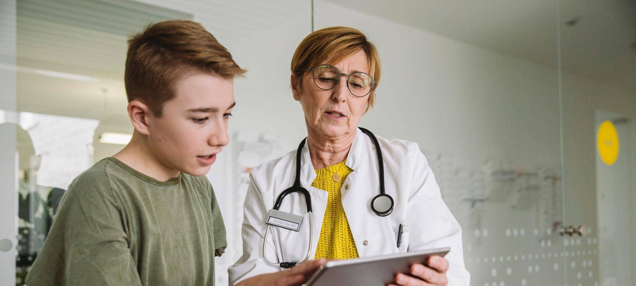 Ärztin schaut mit einem Jungen auf ein Tablet